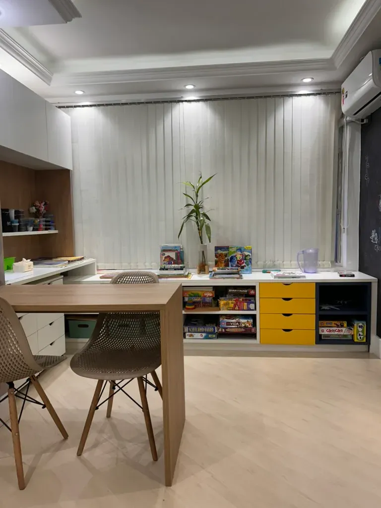 Vista ampla do consultório com mesa, jogos e materiais lúdicos